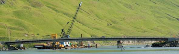 Telephoto view of east side of Bridge to the Other Side, and construction on other side, from across Iliuliuk Harbor