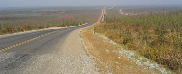 Another paved highway segment, with entirely-elevated pipeline in the background to the right