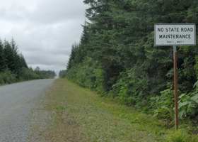 Unpaved Dangerous River Road, with warning sign on lack of winter road maintenance